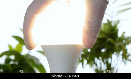 Electrician's Hand Rotates a Led Bulb in Electrical Socket Turning On the Light Stock Photo