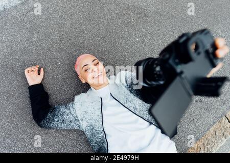 Photographer lying on ground and taking selfie with camera