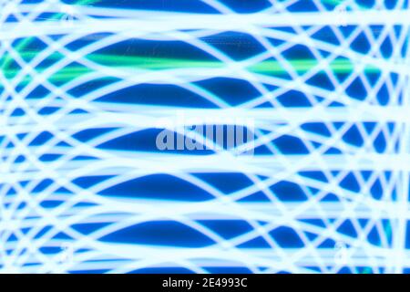Abstract background created by repetitive curve pattern of white and green lights photographed outdoors at twilight. Stock Photo