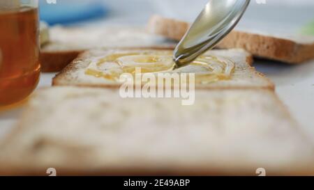 Morning Breakfast with Man Spreading Sweet Honey on the Toast, Fresh Honey on a Slice of Bread in the Kitchen Stock Photo