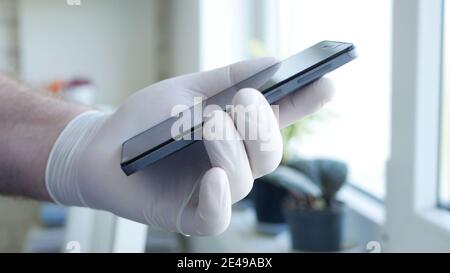Image Doctor's Hand Wearing Protective Glove Using a Smartphone Stock Photo