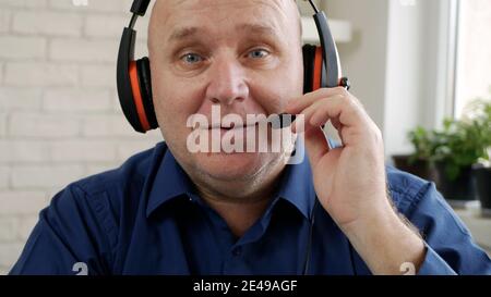 Man Working from Home and Talking in a Video Call Using Laptop Webcam and Headphones, Social Distancing in Covid-19 Pandemic, Remote Working from Home Stock Photo