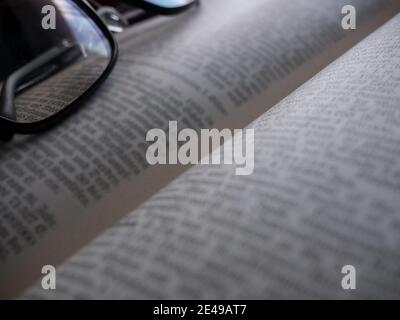 Glasses lying on an open book - intentionally blurred text Stock Photo