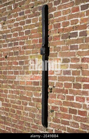 Old vertical wall anchor in the masonry facade of old yellow, orange and red bricks in a restored church Stock Photo