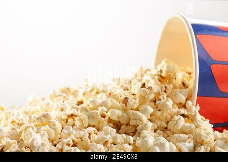 Popcorn spilled of paper box on white background. Concept of cinema. Stock Photo