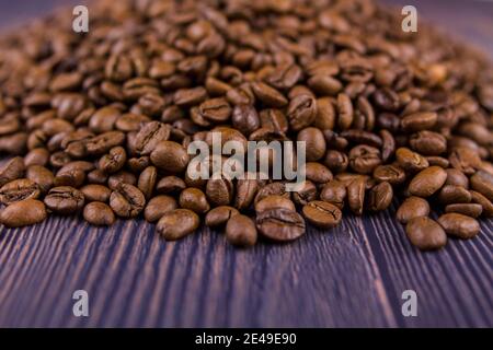 a many coffee beans lie on a wooden table Stock Photo