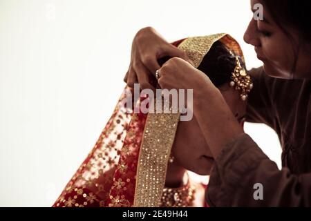 friend help indian bride prepare veil and sari for traditional wedding Stock Photo