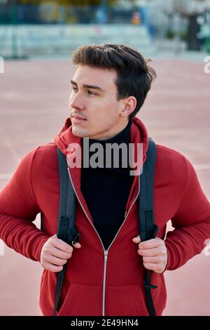 Handsome young student man with a backpack looks to the side Stock Photo