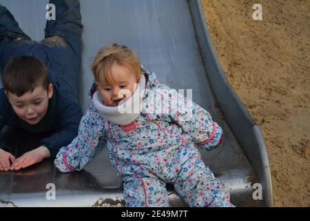 Fun At The Park - Brother And Sister Playing On The Slide  - Siblings Playing - Friends - UK Stock Photo