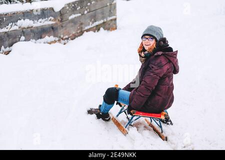 Young Woman is riding seldge at mountain track in winter having fun, Oberaudorf, Hocheck, German Alps, Europe, Stock Photo