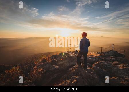 Hiker standing on Top of großer Arber Mountain looking into far and first Sunlight in the morning, Bavarian Forest, Bavaria, Germany, Europe, Stock Photo