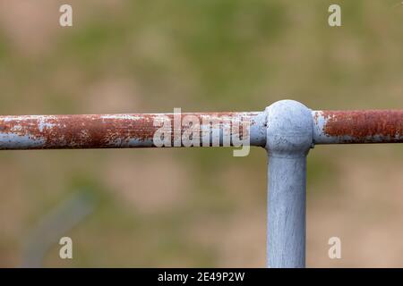 A rusty steel galvanised fence post and hand rail on a green grass background Stock Photo