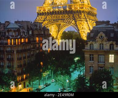 Europe, France, Paris, Eiffel tower, La Tour Eiffel, lit up at night close up view with Parisian street below for scale Stock Photo