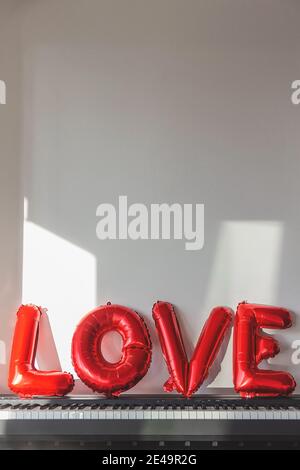 Red balloons in the shape of the word love on a home piano Stock Photo