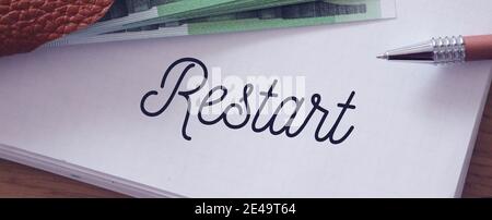 Restart wrd on a page of copybook and 100 Euro bills. Business rebranding concept. Stock Photo