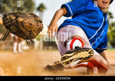 Cropped photo of softball player sliding into home plate Stock Photo