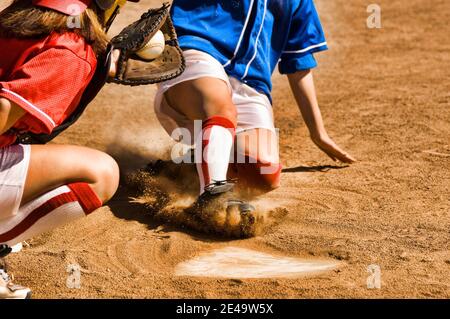 Cropped photo of softball player sliding into home plate Stock Photo