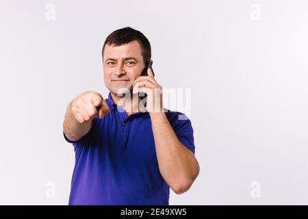 Caucasian man talking on a cell phone and shows his index finger to the camera. White background and side space for your advertisement Stock Photo