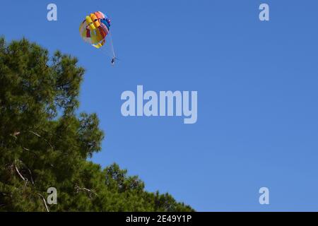 Recreational parakiting background - silhouetes of man under parachuting canopy towed behind a boat. Parasailing in the sky above the Mediterranean se Stock Photo