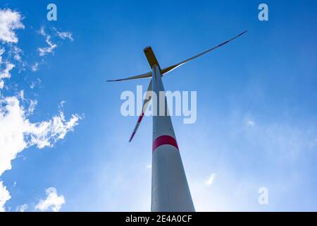 Wind turbine view with blades spinning around under a beautiful blue cloudy sky Stock Photo