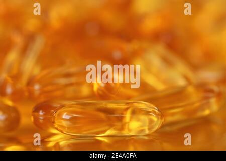 fish oil capsules close-up heap on gold background.Fish oil in gelatin capsules. Omega three.Supplements for a healthy diet. Healthy fats  Stock Photo