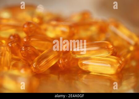 fish oil capsules close-up heap on blurred gold background.Fish oil in gelatin capsules. Omega three.Supplements for a healthy diet. Healthy fats  Stock Photo