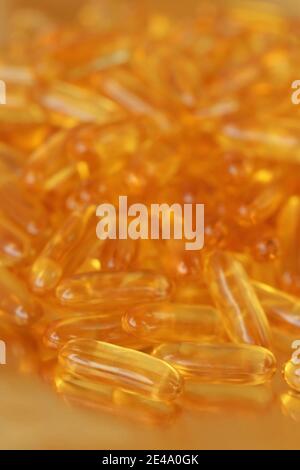 fish oil capsules heap on blurred gold background.Fish oil in gelatin capsules. Omega three.Supplements for a healthy diet. Healthy fats  Stock Photo