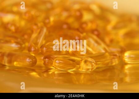 fish oil capsules close-up on blurred gold background.Fish oil in gelatin capsules. Omega three.Supplements for a healthy diet. Healthy fats  Stock Photo