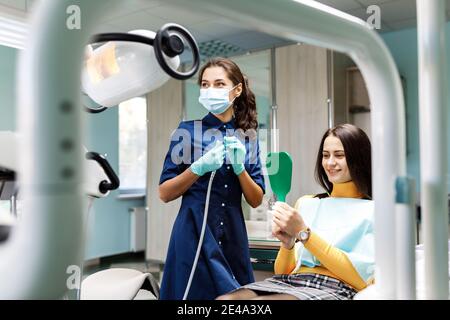 The beautiful young woman is at the dentist. She sits in the dentist's chair and the dentist carefully examines the patient's teeth. The dentist Stock Photo