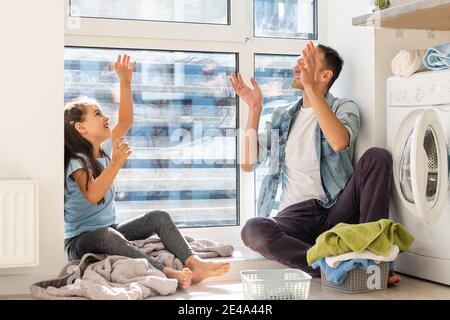 Happy Family loading clothes into washing machine in home Stock Photo