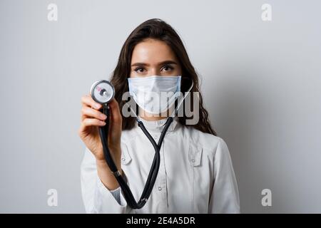 Doctor in medical mask with phonendoscope does auscultation to patient. Medical therapy and treatment. Research and testing for coronavirus covid-19 Stock Photo