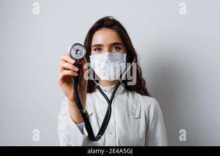 Doctor in medical mask with phonendoscope does auscultation to patient. Medical therapy and treatment. Research and testing for coronavirus covid-19 Stock Photo