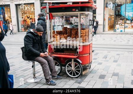 TURKEY, ISTANBUL, DECEMBER 14, 2018: Seller and cart with national Turkish bagels Simits on Istiklal street. Stock Photo