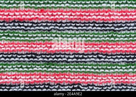 Close-up of hand made knitted stitch wool pattern in red, white, black and green. Stock Photo