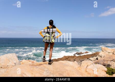 Fit afrcan american woman wearing backpack hiking on the coast Stock Photo