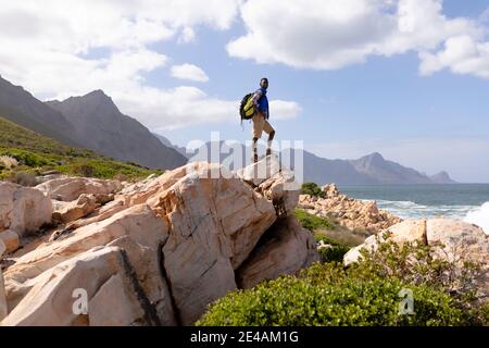 Fit afrcan american man wearing backpack hiking on the coast Stock Photo