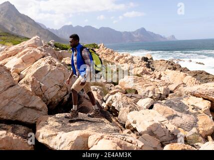 Fit afrcan american man wearing backpacks hiking on the coast Stock Photo