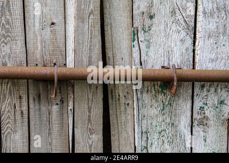 Wooden gate locked with a rusted iron bolt Stock Photo