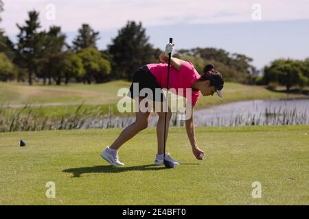 Caucasian woman playing golf leaning to place ball before taking a shot Stock Photo