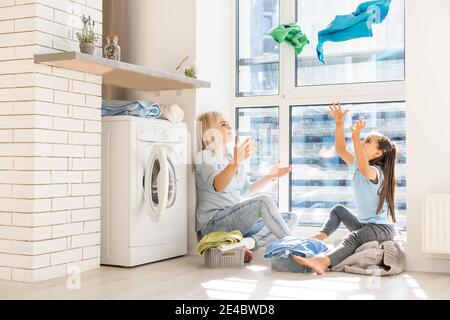 Young housewife and little girl doing laundry together Stock Photo