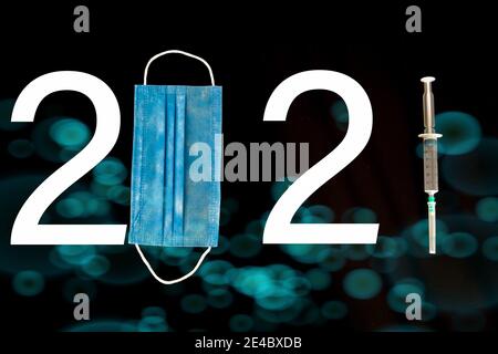 The number 2021 written with mask, number and syringe. A design considered due to Covid-19. Different symbols in the background. 2021 year themed. Stock Photo