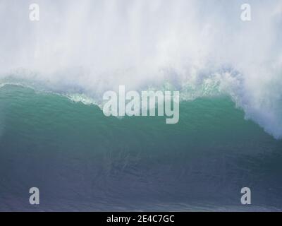 Closeup ocean wave breaking, crashing, with spray flying off the top, backlit by the sun Stock Photo