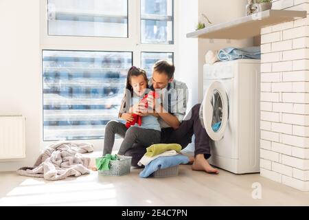 Happy Family loading clothes into washing machine in home Stock Photo