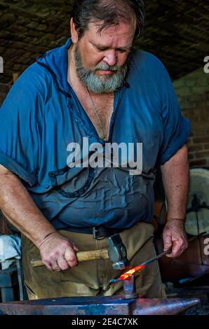 Blacksmith Ralph Oalmann manipulates a heated piece of metal in his shop at Fort Gaines, Aug. 5, 2017, in Dauphin Island, Alabama. Stock Photo