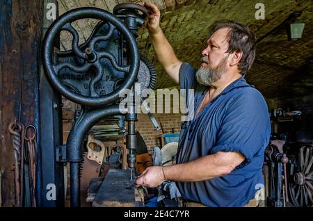Blacksmith Ralph Oalmann uses an antique drill press in his shop at Fort Gaines, Aug. 5, 2017, in Dauphin Island, Alabama. Stock Photo