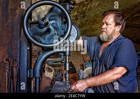 Blacksmith Ralph Oalmann uses an antique drill press in his shop at Fort Gaines, Aug. 5, 2017, in Dauphin Island, Alabama. Stock Photo