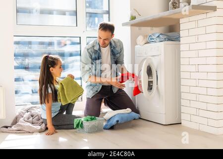 Happy Family loading clothes into washing machine in home Stock Photo