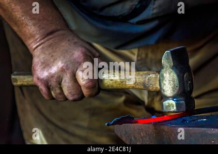 Blacksmith Ralph Oalmann manipulates a heated piece of metal in his shop at Fort Gaines, Aug. 5, 2017, in Dauphin Island, Alabama. Fort Gaines frequen Stock Photo