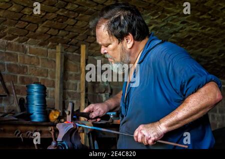 Blacksmith Ralph Oalmann manipulates a heated piece of metal in his shop at Fort Gaines, Aug. 5, 2017, in Dauphin Island, Alabama. Stock Photo