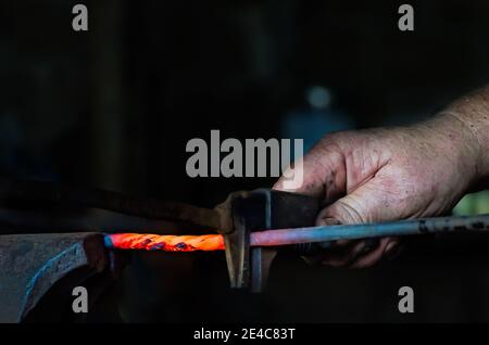 Blacksmith Ralph Oalmann manipulates a heated piece of metal in his shop at Fort Gaines, Aug. 5, 2017, in Dauphin Island, Alabama. Stock Photo